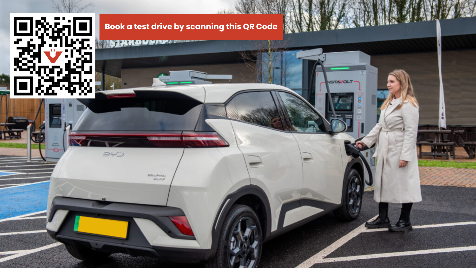 Woman charging at InstaVolt charger with QR code to book a BYD Dolphin Surf Test Drive