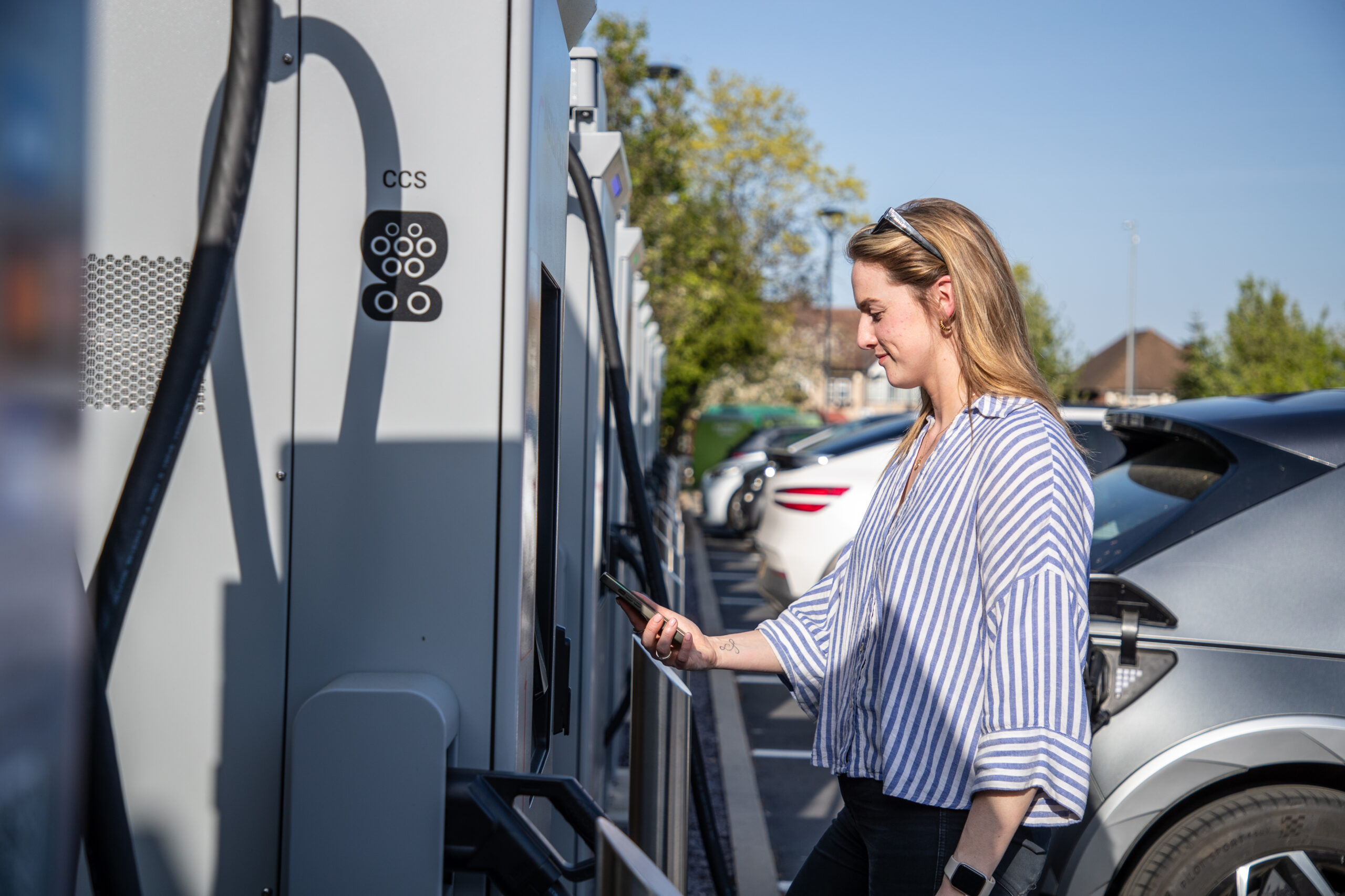 Blonde woman charging an electric vehicle at an InstaVolt charger